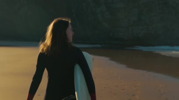Authentiek shot van surfer wandeling op zonsopgang strand — Stockvideo