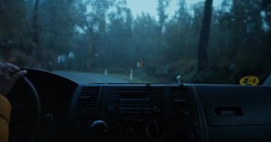 Yağmurlu ve sisli yolda araba süren kadının görüntüsü.