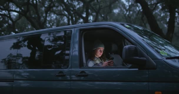 Kobieta siedzi w samochodzie, ekran oświetlony twarzą z telefonem — Wideo stockowe
