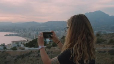 Kadın şehir manzarasının fotoğraflarını çeker.