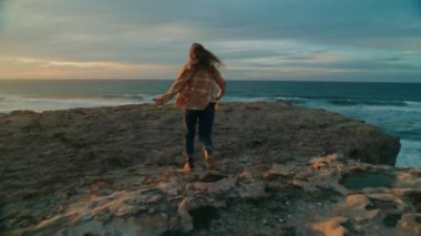 Mutlu özgür kadın gün batımında okyanusa koşar
