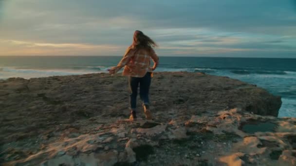 Szczęśliwa wolna kobieta biegnie nad ocean o zachodzie słońca — Wideo stockowe