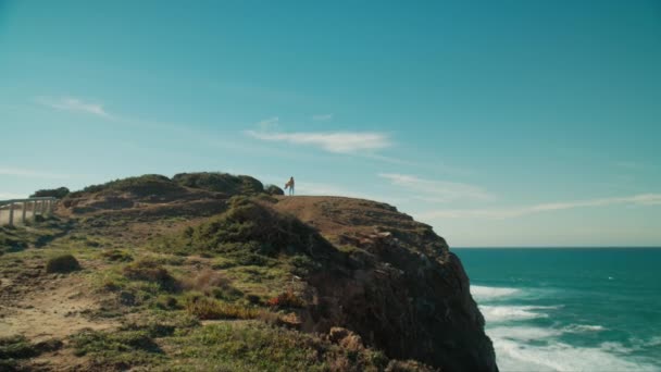 Woman stand on edge of ocean cliff with phone — Wideo stockowe