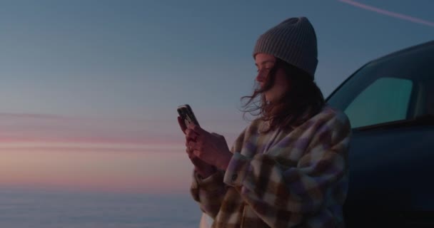Belle jeune femme avec un téléphone au coucher du soleil — Video