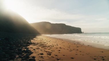 Sessiz, görkemli bir sabah kumsalı, gün doğumu manzarası.