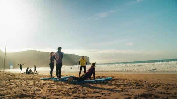 Группа начинающих серферов учится серфингу на пляже — стоковое видео