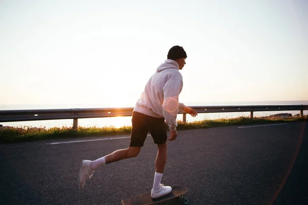 Millennial hipster człowiek jeździć longboard na epickiej drodze — Zdjęcie stockowe