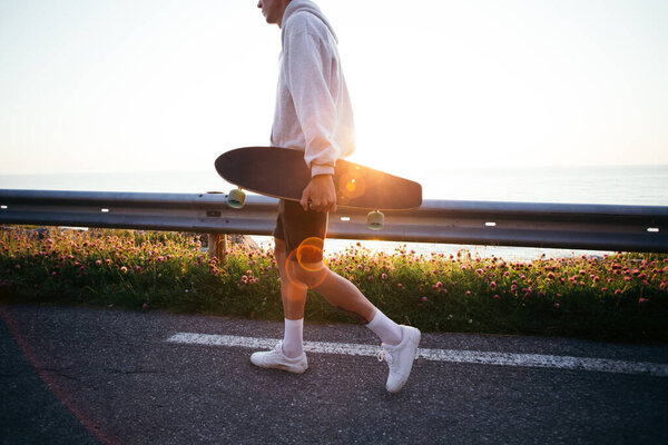 Young hipster man carry longboard at sunset Royalty Free Stock Images