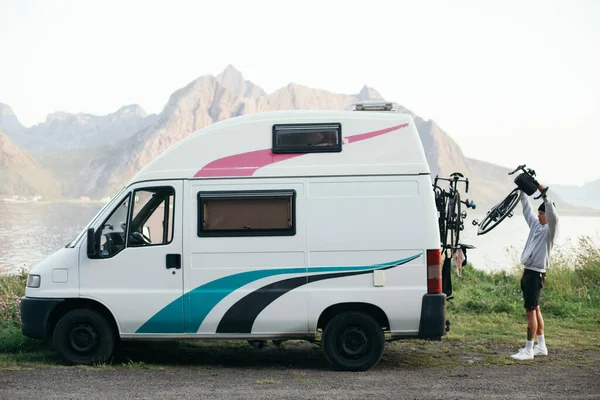 Man attaches bikes to bike rack on camper RV van — Stock Photo, Image