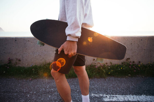 Young hipster man carry longboard at sunset Stock Photo