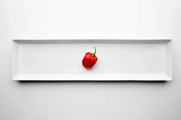 Пряный маленький красный перец, выделенный на длинном белом блюде — стоковое фото