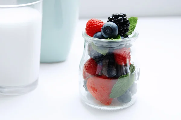 Close up berries and mint in jar and glass of milk — Stock Photo, Image