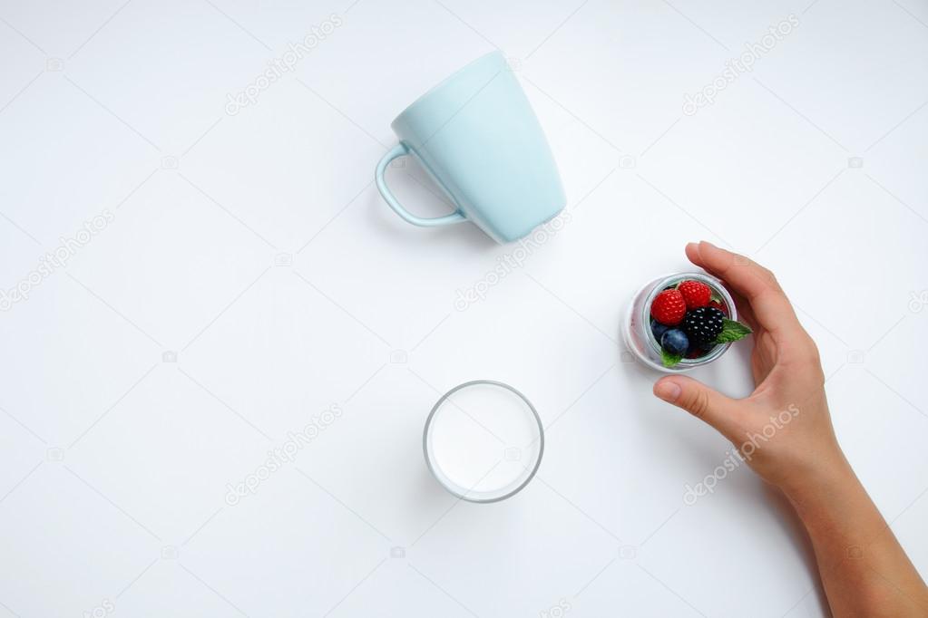 Hand takes jar filled with tasty berries with mint leaves