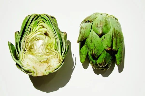 Artichoke half split on white table direct sunlight shadows — Stock Photo, Image