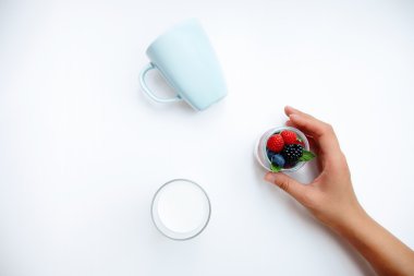 Kavanoz çilek beyaz masaya hafifçe ile el tutar