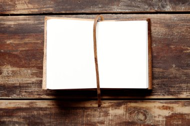 Yukarıdan ahşap bir masa üzerinde deri kapaklı defter açmak