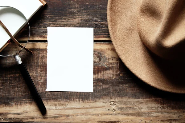 Hoja del sombrero de papel y cuaderno con lupa en una mesa de madera — Foto de Stock