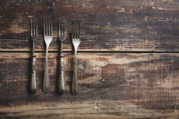 Cuatro tenedores sobre una mesa de madera — Foto de Stock