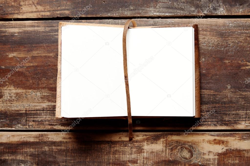 open notebook with leather cover on a wooden table from above