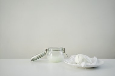 Fresh mozarella on white souser and jar with brine