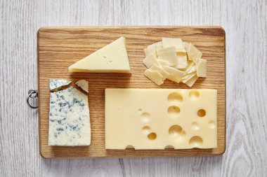 four cheeses on white wooden table and chopping board