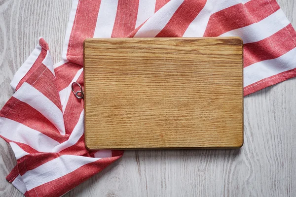 Wooden chopping board on brushed white table with striped kitche