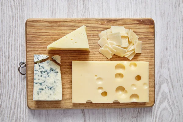Vier Käsesorten auf weißem Holztisch und Schneidebrett — Stockfoto