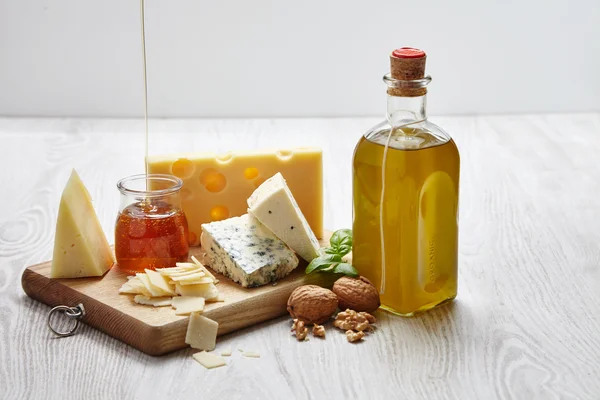 Four cheeses with supplements on chopping board an white wooden — Φωτογραφία Αρχείου