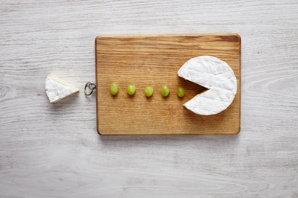 Camembert, formaggio morbido, tagliato come pacman mangiare uva verde — Foto Stock