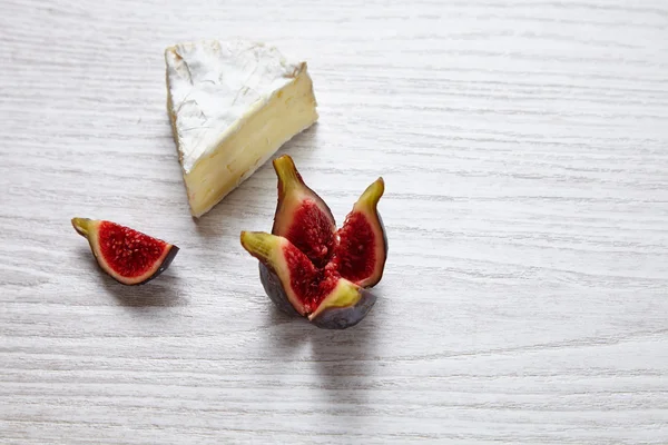 Camembert-Stück mit geteilten Feigen auf weißem Holztisch — Stockfoto