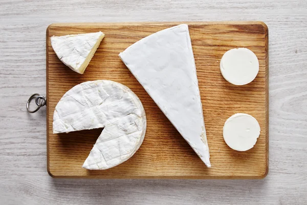 Avangard beyaz yumuşak peynirler: keçi, brie, ahşap masa üzerinde camembert — Stok fotoğraf