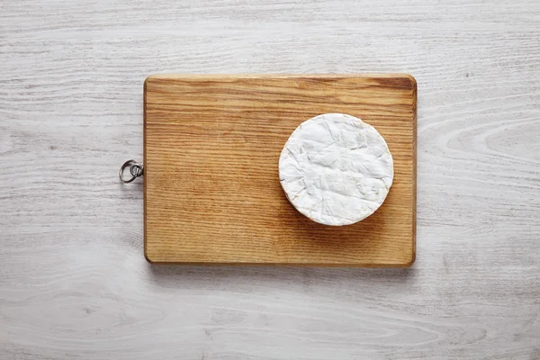 Camembert en el lado de la tabla de madera de corte en blanco cepillado —  Fotos de Stock