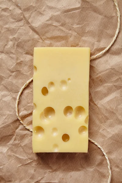 Emmental cheese isolated on craft brown paper with rope top view