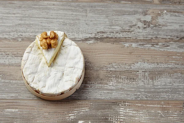 Camembert in wooden box on grunge table with hazelnut top view — Stockfoto