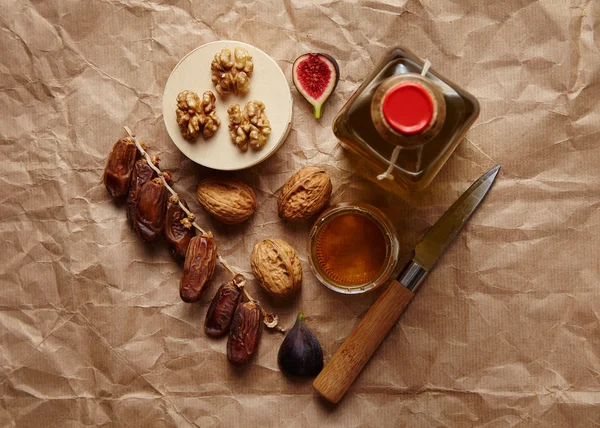 Дати, волоські горіхи, інжир та оливкова олія на ремеслі коричневий папір вид зверху — стокове фото