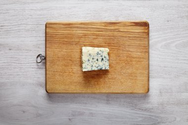 One piece of fresh roquefort cheese on wooden board clipart