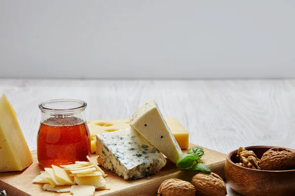 Plateau de fromage avec noix basilic et miel devant panneau d'affichage od — Photo