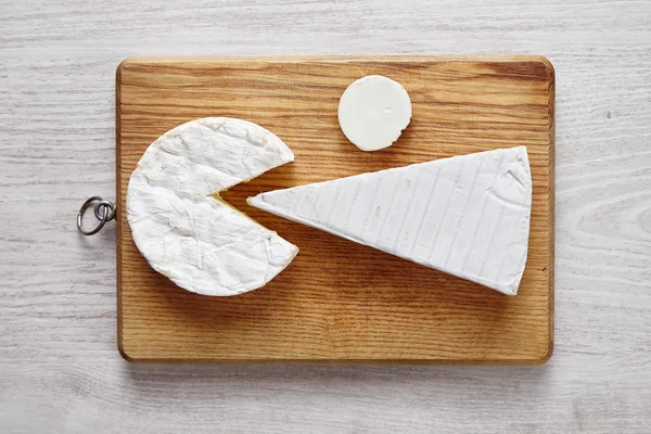 Arte de queijo moderna em placa de corte em mesa de madeira branca — Fotografia de Stock