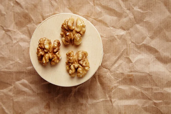 Очищенные грецкие орехи на деревянном круге на коричневой бумаге — стоковое фото