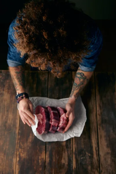 Very top view curly head butcher packing steaks in paper — Stock Photo, Image