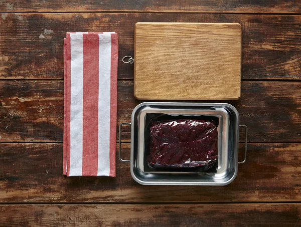 Vacuum pack of whale meat steak metal pot with towel and wooden plate — Stock Photo, Image