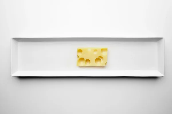 Ladrillo de queso Emmental o Maasdam aislado en placa blanca —  Fotos de Stock