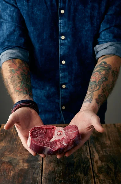 Two tattooed hands holds meat steak gently — Stock Photo, Image