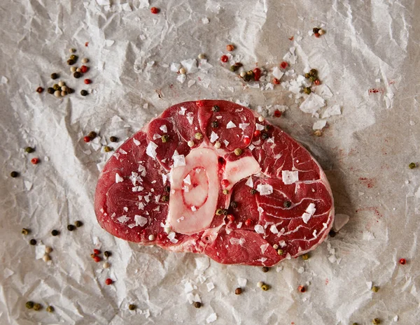 Vista dall'alto della bistecca di carne salata e pepata su carta artigianale — Foto Stock