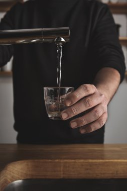 Barista fills small glass with water clipart