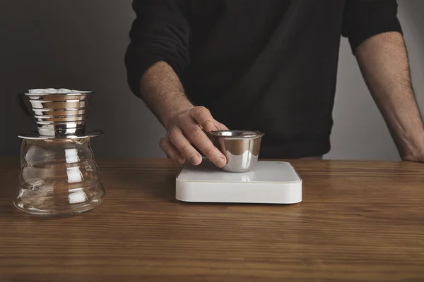 Barista holds cup with ground coffee above weights — Stock Photo, Image