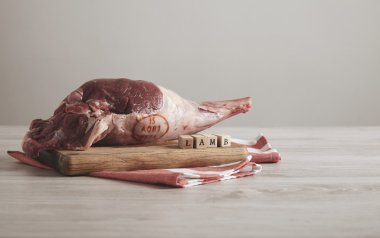 raw meat lamb leg with letters on white table