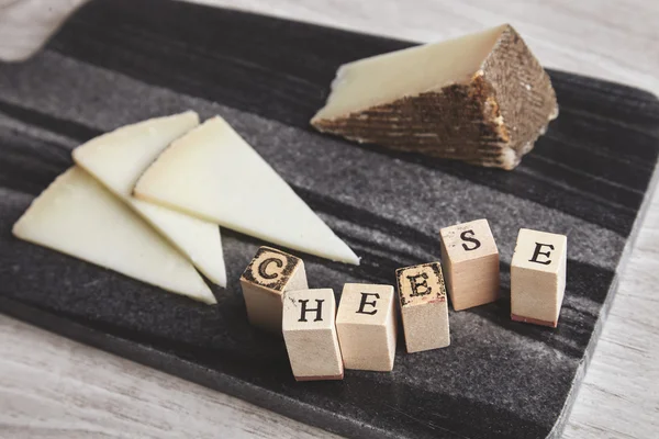 Nahaufnahme Seite Buchstaben Käse vor unkonzentrierten Ziegenkäse — Stockfoto