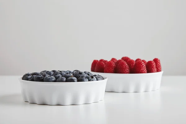 Heap of ripe raspberries blueberries in ceramic bowls — ストック写真