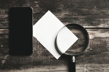 Smartphone, Büyüteç'i ve kağıt levha siyah masada